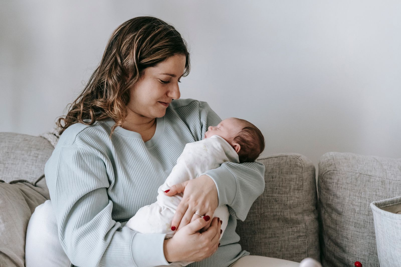 A mother smiling down at her newborn on a couch