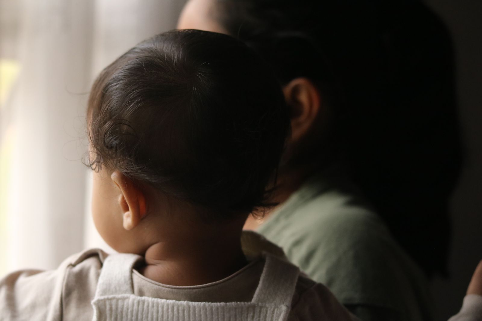 A baby and mother looking quietly out of a window in soft light