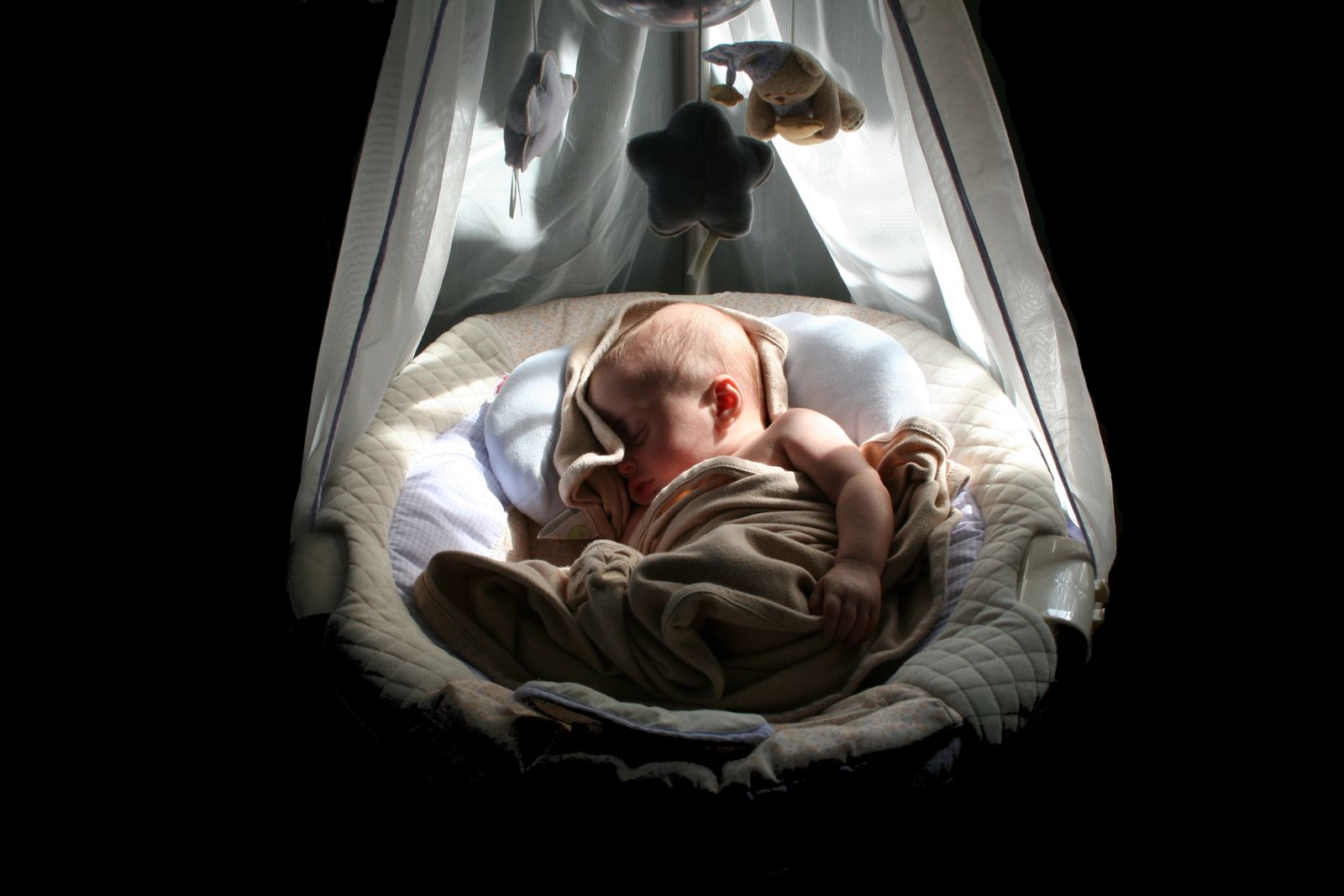 A baby sleeping peacefully in a softly lit cradle